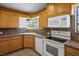 Cozy kitchen featuring wood cabinetry, white appliances, and a window overlooking the backyard at 633 5Th St, Boulder City, NV 89005