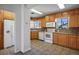 Bright kitchen with wood cabinets, white appliances, and tile flooring with an adjacent refrigerator at 633 5Th St, Boulder City, NV 89005