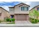 Two-story home featuring a stone veneer garage, blue shutters, desert landscaping, and a brick paver driveway at 6334 Orions Belt Peak St, North Las Vegas, NV 89031