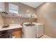 Well-equipped laundry room with modern washer and dryer, shelving and ample countertop workspace at 6334 Orions Belt Peak St, North Las Vegas, NV 89031
