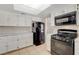 Well-lit kitchen featuring black appliances, white cabinets, and tile flooring at 7004 Powderhorn Cir, Las Vegas, NV 89128
