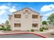 Neutral-colored condo building showcasing the architecture and design of the complex under a bright blue, cloudy sky at 855 N Stephanie St # 2121, Henderson, NV 89014