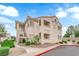 Charming condo building with tan stucco and a well-maintained landscape under a bright blue, cloudy sky at 855 N Stephanie St # 2121, Henderson, NV 89014