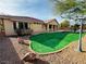Backyard features rock landscaping, artificial turf, and patio cover with lighting at 9092 National Park Dr, Las Vegas, NV 89178