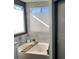 Soaking tub with decorative wood accent and tiled surround under bright window at 9485 Supernova Ct, Las Vegas, NV 89123