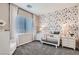 Charming Bedroom featuring floral wallpaper, a white crib, and matching dressers for a cozy and stylish space at 9576 Archer Peak Ct, Las Vegas, NV 89143