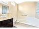 Bright bathroom features a soaking tub with marble surround and a dark vanity with solid surface countertops at 10125 Hope Island Dr, Las Vegas, NV 89134