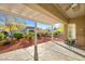 Relaxing covered patio with stone flooring, offering a view of the landscaped backyard with desert plants and trees at 10125 Hope Island Dr, Las Vegas, NV 89134