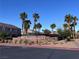 Community entrance with vibrant landscaping, swaying palms, and wrought iron gate for a welcoming feel at 10147 Aspen Rose St # 101, Las Vegas, NV 89183