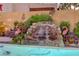 A charming backyard water feature adds tranquility, surrounded by lush plants and greenery near a luxurious pool at 1028 Dodger Blue Ave, Las Vegas, NV 89123