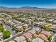 An aerial shot captures a community with houses and lush landscaping against a mountain backdrop at 10353 Yew Blossom Ave, Las Vegas, NV 89166