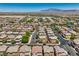 A wide aerial view shows a vast suburban community with mature trees, streets, and mountain views at 10353 Yew Blossom Ave, Las Vegas, NV 89166