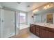 Bright bathroom featuring double sinks, wood cabinets, a bathtub, and a glass shower at 10353 Yew Blossom Ave, Las Vegas, NV 89166