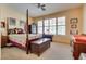 Comfortable bedroom with a four-poster bed and natural light from the window at 10361 Profeta Ct, Las Vegas, NV 89135