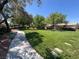 View of a well-maintained front yard with lush green grass and mature trees, complemented by a sidewalk at 10554 Lilac Tree Ave, Las Vegas, NV 89135