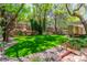 Beautiful backyard with manicured lawn, rock waterfall, brick accents, mature trees and ambient string lights at 108 Quail Run Rd, Henderson, NV 89014