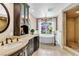 Elegant bathroom featuring dual vanities, a soaking tub under a bright window, and a separate shower with stone accents at 108 Quail Run Rd, Henderson, NV 89014
