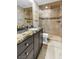 Modern bathroom with granite countertop, dark wood cabinets, glass shower, neutral tiling, and brushed nickel fixtures at 108 Quail Run Rd, Henderson, NV 89014