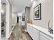 Long hallway with wood floors, white trim, storage cabinet, and access to rooms with marble tile and a black front door at 108 Quail Run Rd, Henderson, NV 89014