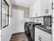 Well-equipped laundry room with modern washer/dryer, white cabinets, dark countertop, and a bright window view at 108 Quail Run Rd, Henderson, NV 89014