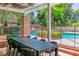 A covered outdoor dining area with a large table, chairs, and a view of the pool and landscaped backyard at 108 Quail Run Rd, Henderson, NV 89014