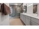 Modern bathroom featuring a glass shower, double vanity with a white countertop and neutral-toned tile flooring at 1957 Regal Bluff Dr, Henderson, NV 89052