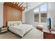 Bright bedroom with a wood accent wall, tall windows, and stylish furniture at 1957 Regal Bluff Dr, Henderson, NV 89052