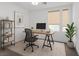 Bright home office with a modern desk, computer, black chair, natural light, and potted plant at 1957 Regal Bluff Dr, Henderson, NV 89052