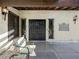 Elegant double front doors with ornate ironwork, side windows, decorative sconce, and a cozy chair on the patio at 2104 Plaza De La Candela, Las Vegas, NV 89102