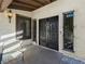 Elegant double front doors with ornate ironwork, side windows, decorative sconce, and a cozy chair on the patio at 2104 Plaza De La Candela, Las Vegas, NV 89102