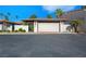 Attached two-car garage with white door, brick trim, and red tile roof, nestled among palm trees and white brick walls at 2104 Plaza De La Candela, Las Vegas, NV 89102