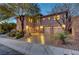 Stunning three-car garage home with stone accents, mature trees, and illuminated windows at dusk at 2124 Pont National Dr, Henderson, NV 89044