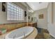 Bathroom showing oval tub design, block glass window, stone detail, and vanity with lighting at 2124 Pont National Dr, Henderson, NV 89044