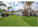 Expansive backyard featuring artificial grass, mature trees, and an outdoor dining area at 219 Windsong Dr, Henderson, NV 89074