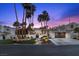 Stunning home exterior at twilight with lush landscaping, swaying palm trees, and a private gated entrance at 219 Windsong Dr, Henderson, NV 89074