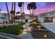 Beautiful home featuring manicured landscaping, an illuminated walkway, and mature palm trees in a desert setting at 219 Windsong Dr, Henderson, NV 89074