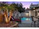 Inviting pool area with red chaise lounges, lush landscaping, and a bar with seating at 219 Windsong Dr, Henderson, NV 89074