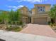 Front exterior of a home featuring a brick driveway, three-car garage, and manicured landscaping at 3 Hilltop Crest St, Henderson, NV 89011