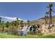 Picturesque waterfall flowing into a pond, surrounded by lush landscaping and palm trees at 3 Hilltop Crest St, Henderson, NV 89011