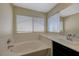 Bathroom featuring a tub with white tile surround and a single sink vanity with dark cabinets at 3034 Scenic Valley Way, Henderson, NV 89052