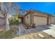 Two-story home with tan stucco and a three car garage with desert landscaping at 3034 Scenic Valley Way, Henderson, NV 89052