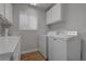 Laundry room featuring white cabinets, updated washer and dryer, and a window at 3040 Hidden Treasure Dr, Las Vegas, NV 89134