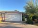 Two-car garage with adjacent landscaping featuring a desert tree and patio chair on a concrete driveway at 3382 Berwyck St, Las Vegas, NV 89121