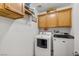 Laundry room with front loading washer and dryer and wooden cabinets above at 3430 Flagstone Ct, Pahrump, NV 89048