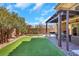 A well maintained backyard with synthetic lawn, brick patio with a grill and pergola, and mature landscaping at 3512 Portiani Dr, Las Vegas, NV 89141