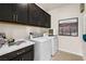 Well-lit laundry room featuring a front load washer, dryer, and dark cabinets for storage at 4250 E Brusca Way, Pahrump, NV 89061