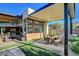 Charming covered patio featuring an outdoor kitchen, comfortable seating, and well manicured artificial turf at 5155 Rock Daisy Dr, Las Vegas, NV 89135