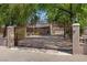 Ornate iron gate leading to a well-manicured front yard with mature trees at 5854 Sheila Ave, Las Vegas, NV 89108