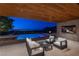 Stylish covered patio with comfortable seating, outdoor TV, and a view of the pool and city lights at 6 Rock Mount Ct, Henderson, NV 89012