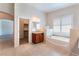 Bathroom featuring a soaking tub, single vanity, and natural light from plantation-shuttered window at 6125 Paddleboat St, North Las Vegas, NV 89031